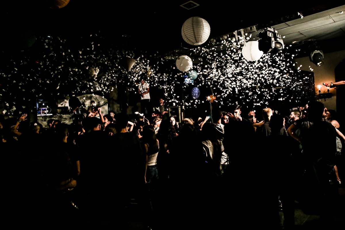 Foule dans une salle sombre avec particules blanches flottantes et lanternes suspendues