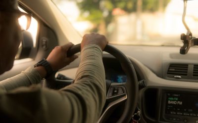 Un homme conduit une voiture, le volant en main, dans la rue