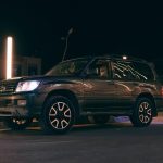 SUV noir stationné sur rue nocturne avec phares allumés